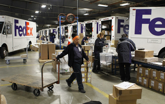 Trabajadores de Fedex preparando sus camiones para entregar paquetes.